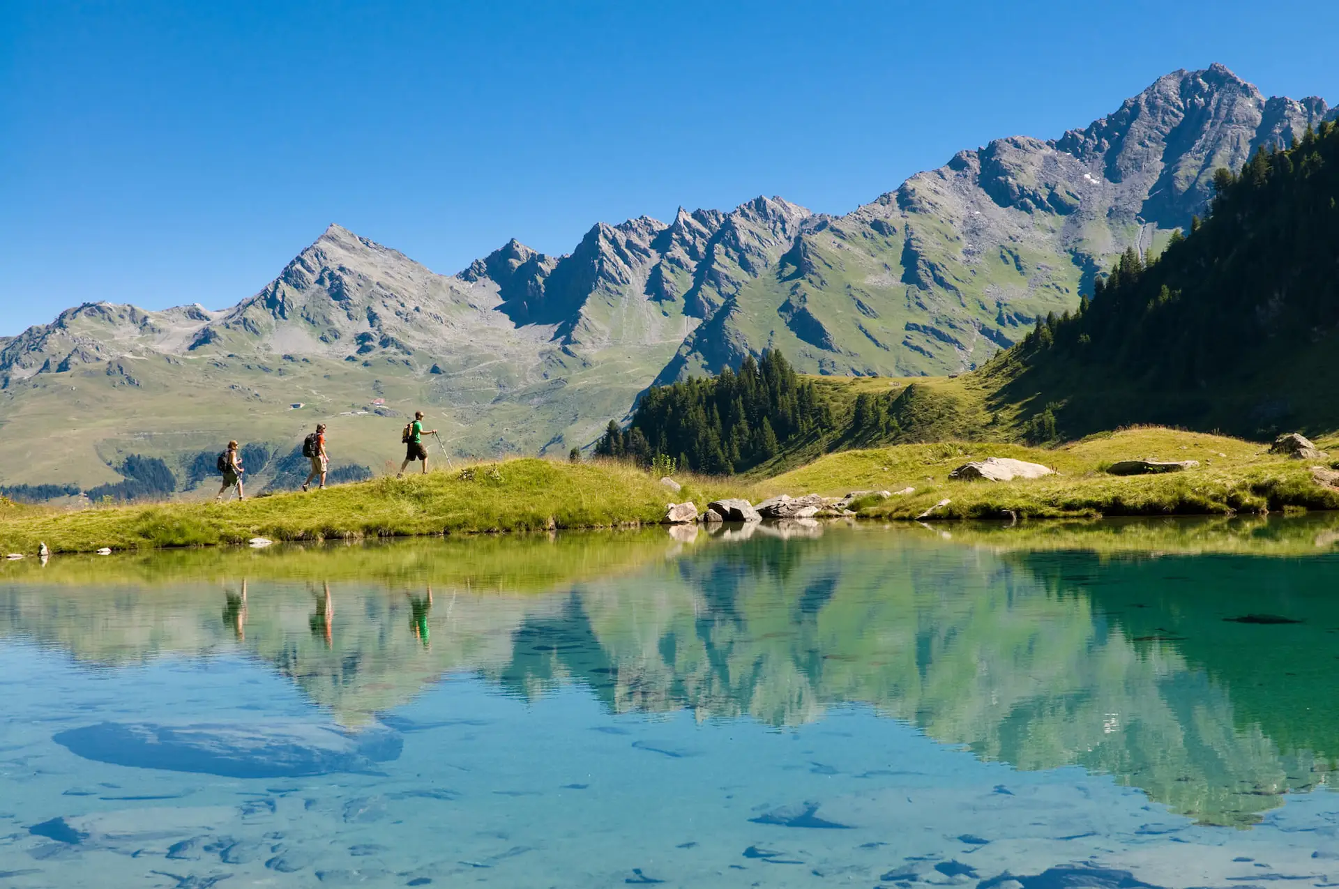 Hikers by a mountain lake above Verbier in summer