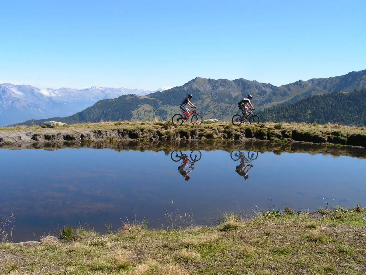 Mountain bikers riding past an alpine lake near Verbier